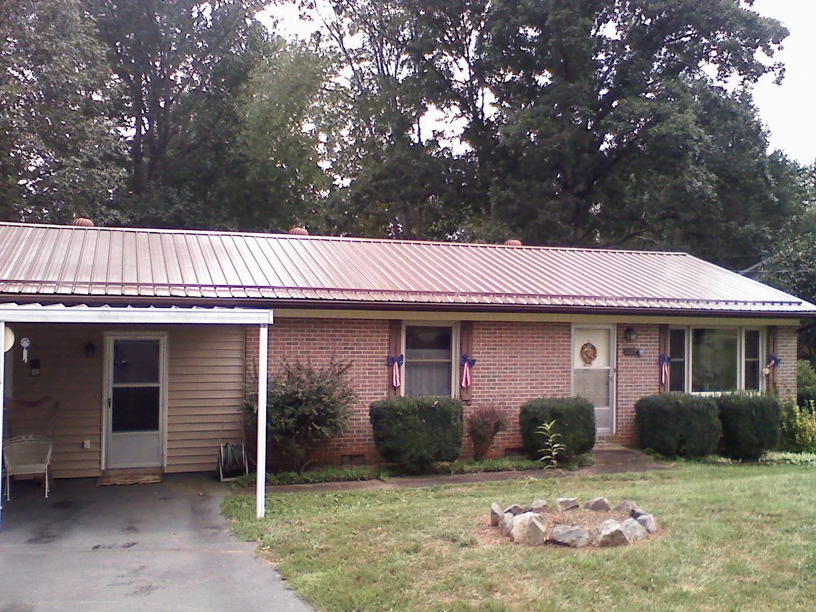 Bronze metal roof and carport on a brick ranch home — Roof Repair work by our crew in Bedford